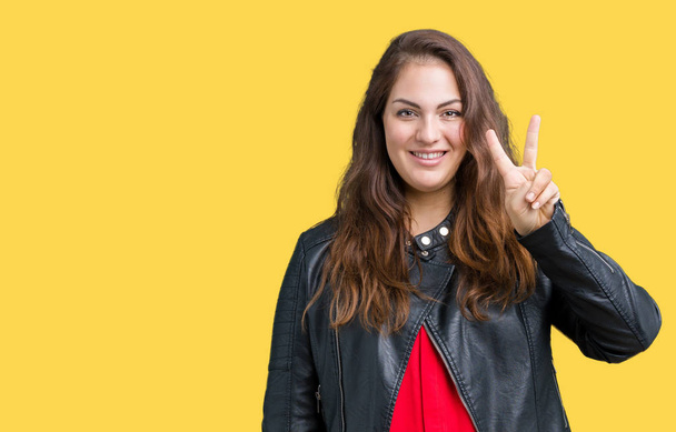 Beautiful plus size young woman wearing a fashion leather jacket over isolated background showing and pointing up with fingers number two while smiling confident and happy. - Foto, immagini