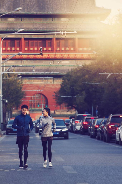 усміхнена спортивна молода пара в спортивному одязі бігає разом на вулиці
 - Фото, зображення
