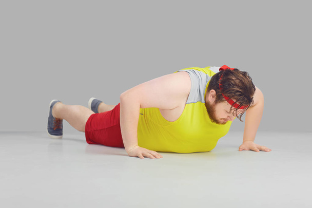 Fat funny guy with a beard doing push up goes for sports. - Foto, Bild