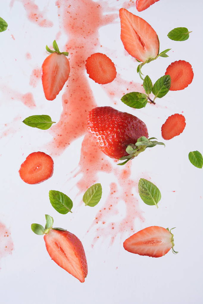 Flying fresh strawberries with mint leaves. Food levitation concept. Creative food layout. - Foto, afbeelding