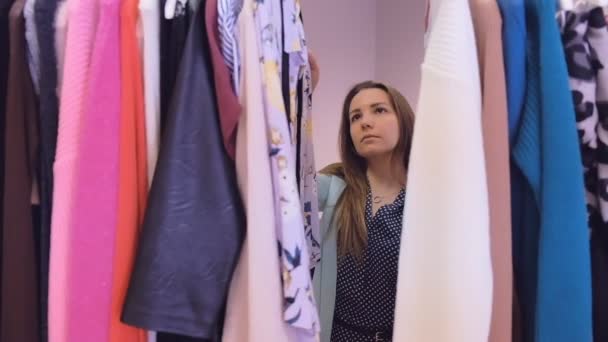 Portret van een jonge charmante vrouw vinden zichzelf nieuwe kleren in een dure boetiek. Ze is het lezen van tags en kiezen. - Video