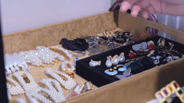 Μια νεαρή γυναίκα διαλέγει σκουλαρίκια από τη συλλογή της. κοσμήματα μόδας, όμορφα αξεσουάρ για κάθε μέρα. - Πλάνα, βίντεο