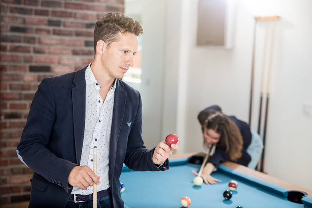 Modern man with pool ball standing next to snooker table. - Fotografie, Obrázek