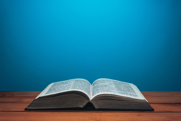 Bible on a red wooden table. Beutiful blue wall background. - Photo, Image