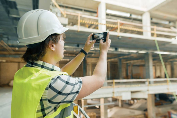 Young male architect photographs a construction site. Building, development, teamwork and people concept - Photo, image