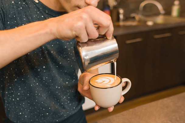 Primo piano di versare il latte cotto a vapore in tazza di caffè, sfondo caffetteria
 - Foto, immagini