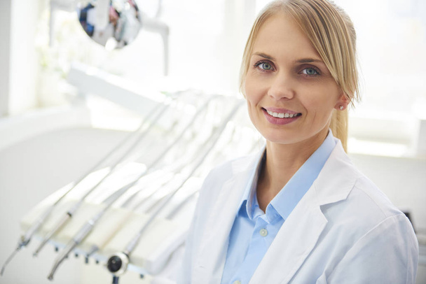 Portret uśmiechniętego dentysty w medycznych mundurach w klinice dentystycznej - Zdjęcie, obraz