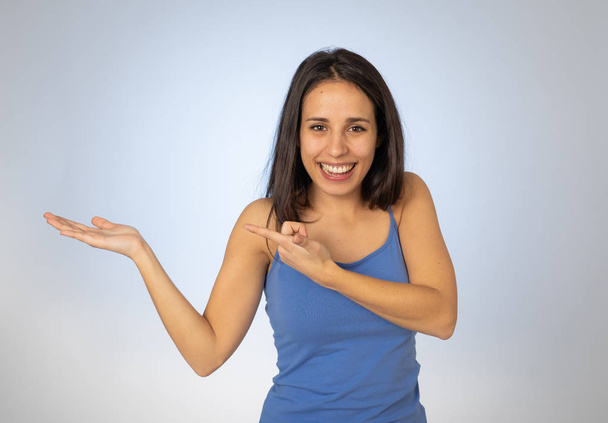 Portrait of happy young woman showing empty copy space on open hand palm looking excited and surprised. Cheerful teenager girl presenting and showing great product in advertisement gesture. - 写真・画像