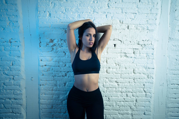 Portrét sportovní ženy, oblečené v tělocvičně, vypadá smyslně a fit. Studiová střela latinsky sexy silné ženy v sportovním oblečení vypadá zdravě na cihlovou zeď. Koncepce péče o tělo. - Fotografie, Obrázek
