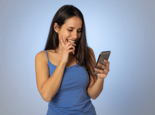 Young latin woman on mobile looking happily shocked at social media app dating site. Teenager girl having lots of followers and likes on online video blog In millennial generation using technology. - 写真・画像