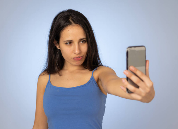 Studio shot of Young cool pretty latin teenager woman taking selfie with mobile smart phone having fun and looking beautiful sexy In millennial generation using mobile and social media addiction. - Photo, Image
