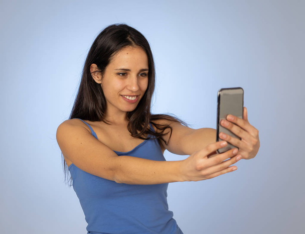 Studio shot of Young cool pretty latin teenager woman taking selfie with mobile smart phone having fun and looking beautiful sexy In millennial generation using mobile and social media addiction. - Φωτογραφία, εικόνα