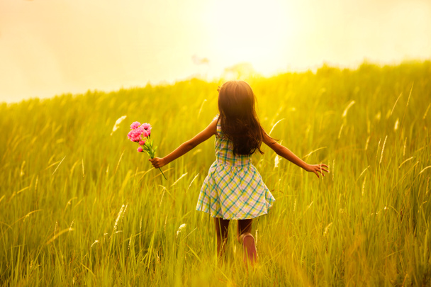 Pieni tyttö juoksee niityllä auringonlaskun kanssa
 - Valokuva, kuva