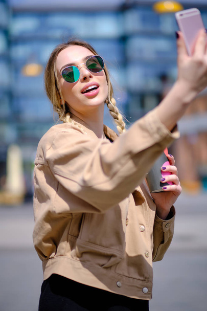 スマート フォンが付いている通りで若い女性 selfie.  - 写真・画像
