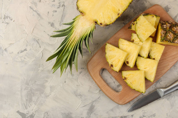 Nagy érett gyümölcs ananász. Ananász szelet-ra egy vágó fedélzet-ra egy könnyű beton háttér. Nyári. felülnézet. - Fotó, kép