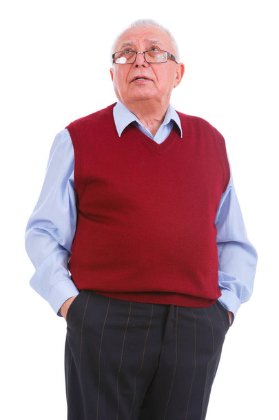 Portrait of thinking senior old teacher man with glasses, holds hands in pockets, cardigan marsala color and shirt, isolated on white background. Human emotions, facial expressions. Education concept - Foto, Imagen