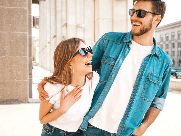 Smiling beautiful girl and her handsome boyfriend in casual summer clothes. Happy cheerful family having fun on the street background in sunglasses - Photo, image