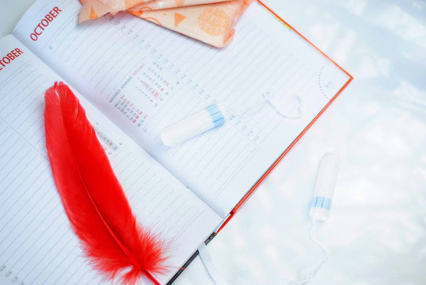 Le mestruazioni. Fodere, assorbenti e calendario con giornate rosse su sfondo bianco
 - Foto, immagini