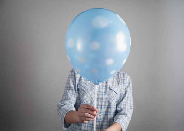 Girl holding balloon in gray background. - Фото, изображение