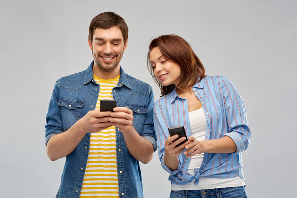 happy couple using smartphones over grey - Фото, изображение