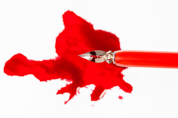 top view of steel nib in dip pen over red ink blot - Photo, Image