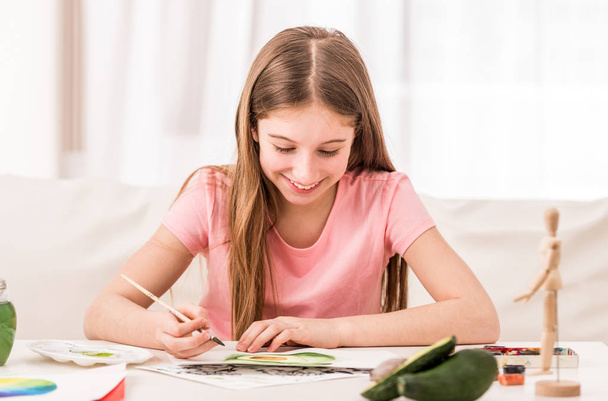Girl smiles when drawing green avocado - Foto, Imagen