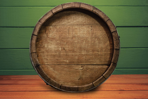 Hermoso barril de madera sobre una mesa de madera roja y fondo de pared de madera verde
. - Foto, Imagen