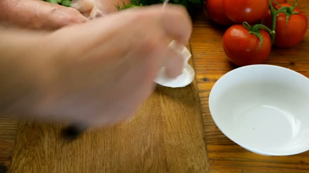 Human hands cut champignon mushrooms on pieces on a wooden kitchen board with a kitchen knife and put in white ceramic bowl. Tomatoes, herbs, meat. - Footage, Video