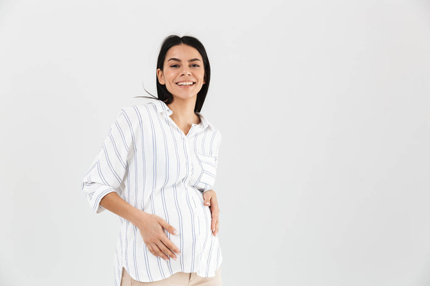 Image of brunette pregnant woman 30s smiling and touching her bi - Zdjęcie, obraz