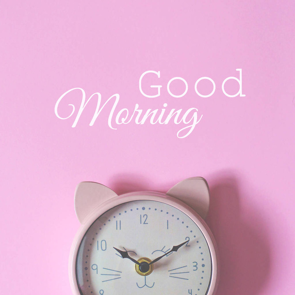 The alarm clock on a pink background and the text good morning. - Photo, Image