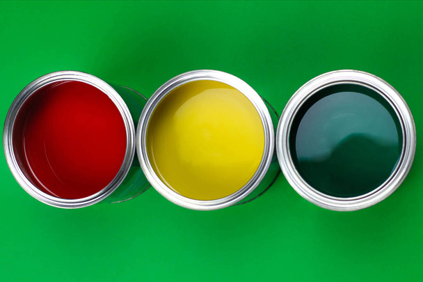 Three open cans of paint on a green background. - Zdjęcie, obraz