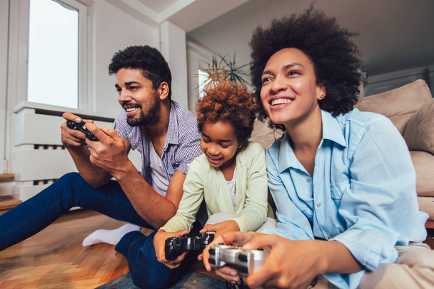 Famille souriante assis sur le canapé ensemble jouer à des jeux vidéo
 - Photo, image