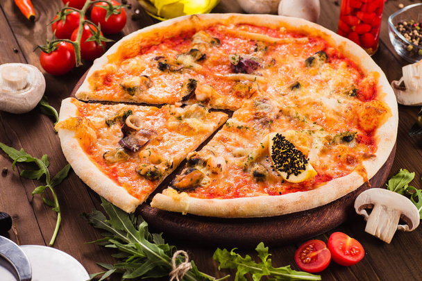 deliciosa pizza italiana de frutos do mar com ingredientes em uma mesa de madeira escura (vista superior). Corte uma peça
 - Foto, Imagem