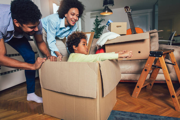Афроамериканская семья, родители и дочь, распаковывают коробки
 - Фото, изображение