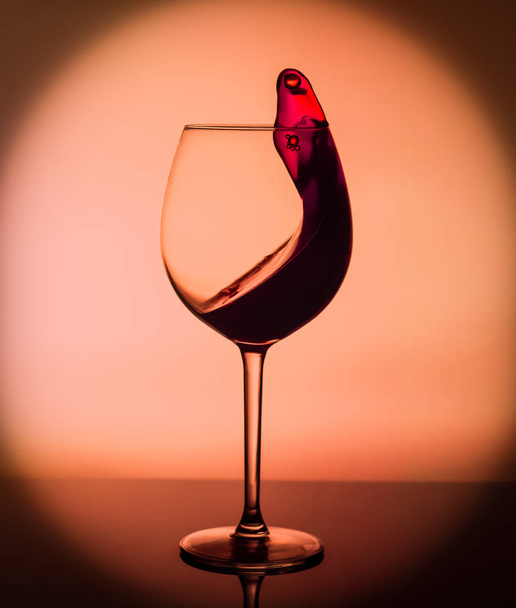 Kieliszek wina z odrobiną wina na żółtym tle. Szklanka na barze w kawiarni, restauracji, klubie nocnym lub dyskotece. - Zdjęcie, obraz