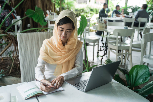 femme avec hijab travaillant à l'aide d'un ordinateur portable
 - Photo, image
