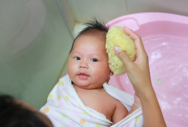Close up hands of mother taking a bath to her newborn baby in a bathtub. - Фото, зображення
