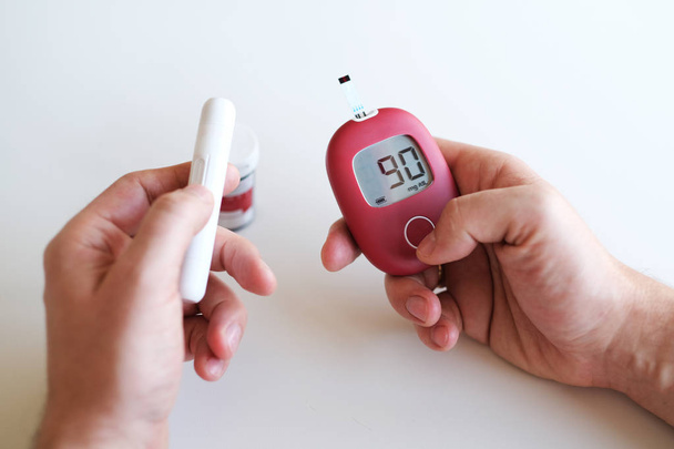 Człowiek chory na cukrzycę, sprawdza jego poziom glukozy przez glukometer. - Zdjęcie, obraz