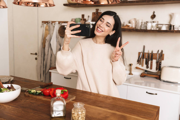 Portrait of smiling brunette woman 30s taking selfie photo on sm - Foto, Bild