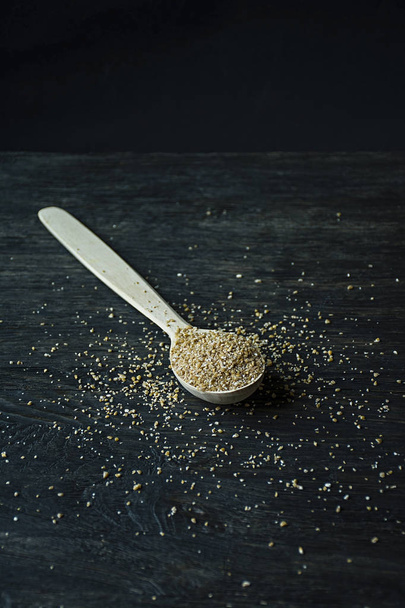 Wheat groats in a wooden spoon on a wooden dark background. Wooden spoon with wheat grains. - Photo, Image