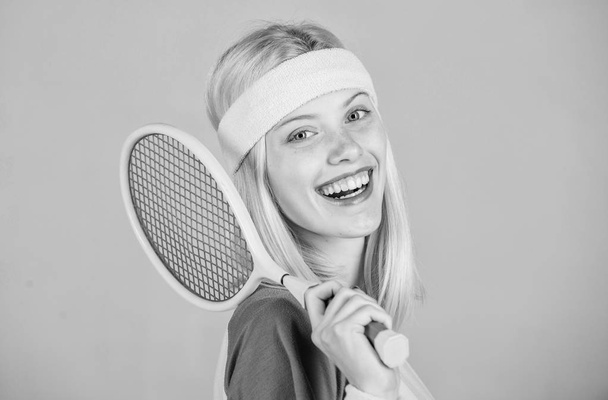 Girl adorable blonde play tennis. Sport for maintaining health. Athlete hold tennis racket in hand on grey background. Tennis club concept. Active leisure and hobby. Tennis sport and entertainment - Valokuva, kuva