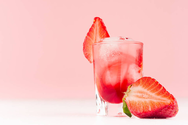 Summer fresh red strawberry drink with ice cubes and slice berry on fashion pastel pink color background and white wood table, copy space. - Photo, image