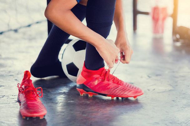 Soccer players sitting and tying red sport shoelaces - Photo, image