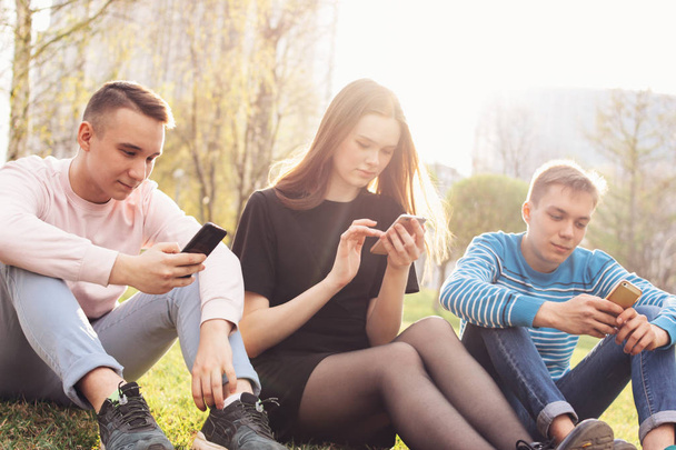 Le groupe de jeunes amis adolescents utilisant le mobile dans la rue de la ville
 - Photo, image
