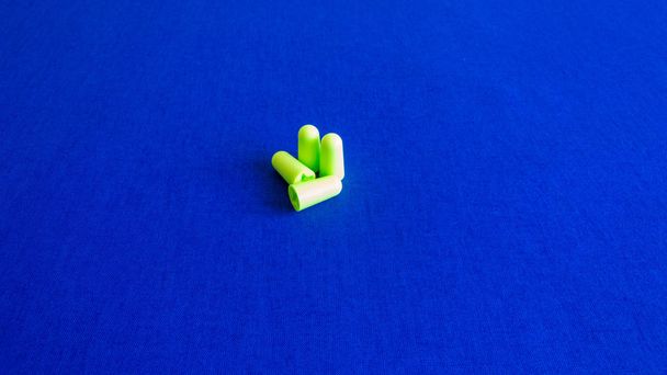 Green earplugs on blue background - image - Фото, изображение