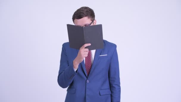 Young businessman covering face with book - Materiaali, video