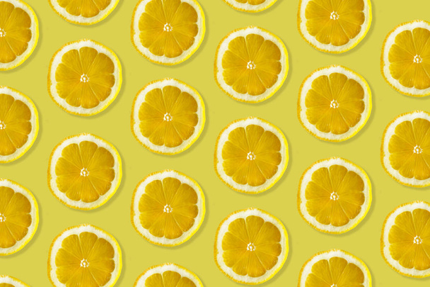 Kreatives Muster aus Zitrone. Draufsicht auf frische Zitrusscheiben auf farbenfrohem gelben & orangefarbenen Hintergrund.  - Foto, Bild