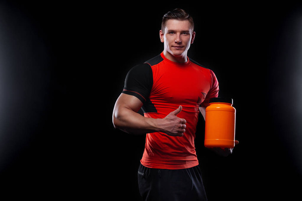 glücklicher und gesunder muskulöser junger Fitnesssportler mit einem Glas Sporternährung - Protein, Gainer und Kasein. - Foto, Bild