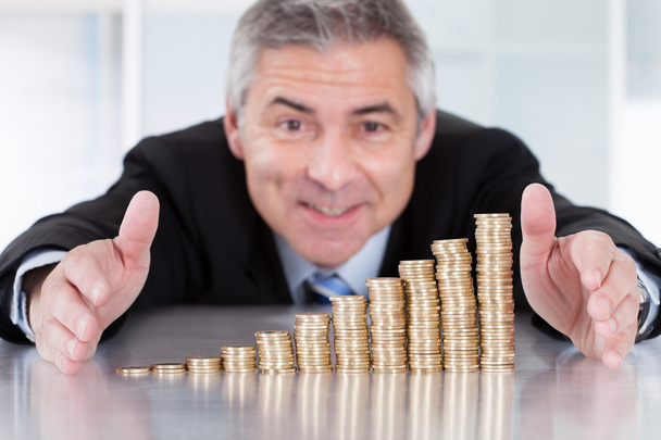 Mature Businessman With Stack Of Coins - Foto, immagini