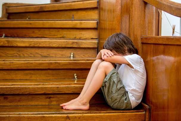 Sad child, sitting on a staircase in a big house, concept for bu - Foto, imagen